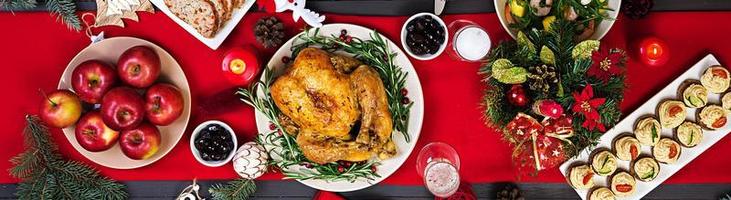 Baked turkey. Christmas dinner. The Christmas table is served with a turkey, decorated with bright tinsel and candles. Fried chicken, table.  Family dinner. Top view photo