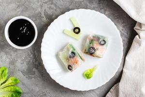 Spring roll cut in half in rice paper with seafood and vegetables on a plate. Top view. Close-up photo