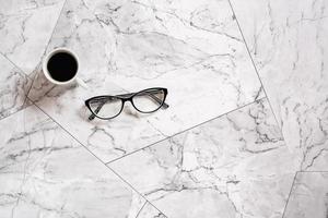 A cup of black coffee and glasses on a marble tile. Pause at work. Scandinavian house design photo