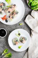 Spring roll cut in half in rice paper with seafood and vegetables on a plate. Top an vertical view. photo