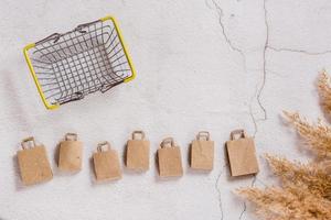 Kraft paper shopping bags in a row and a basket on a concrete background. Top view. photo