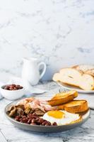 Traditional English breakfast with egg, bacon, beans, mushrooms and toast on a plate. Vertical view photo