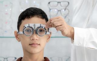 Boy has his eyes checked for glasses by a specialist. photo