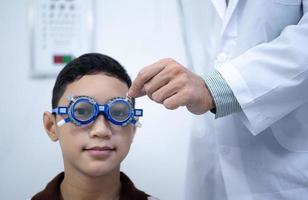 Boy has his eyes checked for glasses by a specialist. photo