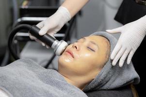 mujer joven haciendo masaje facial en clínica de belleza. foto