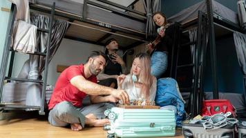 Groups of travelers of different nationalities having fun in the hostel. photo