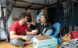 Groups of travelers of different nationalities having fun in the hostel. photo