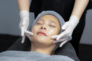 mujer joven haciendo masaje facial en clínica de belleza. foto