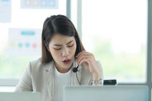 Young asian woman working at a call center Consulting about stock investment information with customers calling for advice with emotion of serious photo
