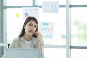 Young asian woman working at a call center Consulting about stock investment information with customers calling for advice with emotion of serious photo