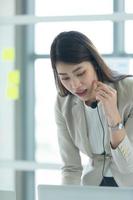 Young asian woman working at a call center Consulting about stock investment information with customers calling for advice with emotion of serious photo