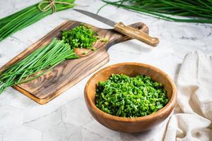 Fresh chopped green onions in a wooden bowl and a cutting board on the table. Vitamin herbal diet photo