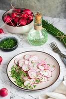 Fresh radish and green onion salad on a plate on the table. Home cooking. Vertical view photo