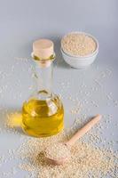 Sesame oil in a glass and seeds in a bowl on the table. Organic Alternative Food. Vertical view photo