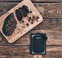 The best freshly baked bread. High angle shot of freshly baked bread and closed menu lying on rustic table photo