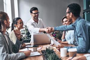 Welcome on board Two men in smart casual wear shaking hands and smiling while working in the creative office photo