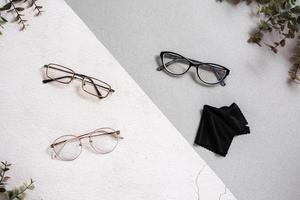 Several types of eyeglasses and a cleaning cloth on a two-tone background. photo