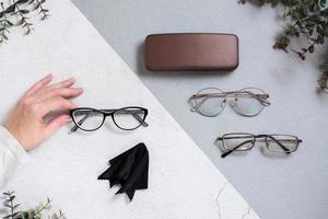 A woman's hand shows a set of glasses and a napkin on a two-tone background. photo