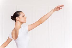 hermosa bailarina. confiada joven bailarina en tutú blanco bailando en el estudio de ballet foto