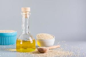 Sesame oil in a bottle and sesame seeds in a bowl on the table. Organic Alternative photo