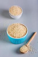 Sesame seeds in bowls and in a wooden spoon on a gray background. Organic food. Vertical view photo