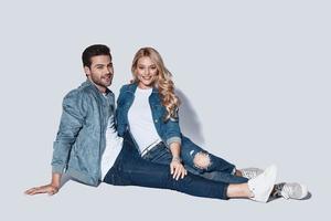 In love. Beautiful young couple looking at camera and smiling while sitting against grey background photo