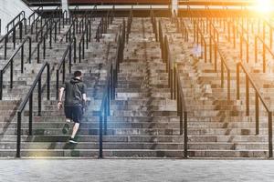 Achieving best results. Full length rear view of young man in sport clothing running up the stairs while exercising outside photo