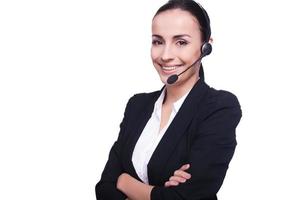 Representante de Servicio al Cliente. mujer joven segura de sí misma con auriculares sonriendo y manteniendo los brazos cruzados mientras está aislada en blanco