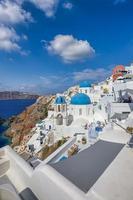 vista de la ciudad de oia en la isla de santorini en grecia. famoso paisaje griego, cúpulas azules sobre arquitectura blanca. destino de vacaciones de verano de lujo, viaje romántico escénico. hermoso paisaje urbano y mar azul foto