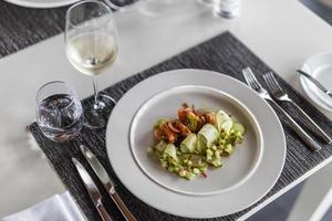 Luxury gourmet appetizer of cucumber rolls with shrimps and closeup vegetables on elegant white plate. horizontal table top, white wine. Cuisine luxurious dinner salad, appetizer meal photo