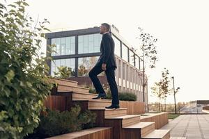 Confident mature man in full suit walking up by staircase outdoors photo