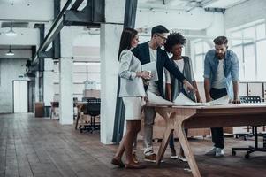 Passionate about their project. Group of young business people working together in creative office while standing near the wooden desk photo