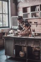 la creatividad está en sus venas. joven alegre y niño pequeño haciendo vasijas de cerámica en la clase de cerámica foto