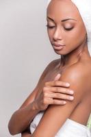 Pure beauty. Beautiful young Afro-American shirtless woman touching her face and keeping eyes closed while Isolated on gray background photo