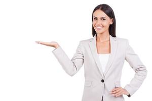 Copy space on her hand. Confident young businesswoman in suit holding copy space in her hand smiling while standing against white background photo