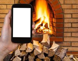 tourist photographs fireplace on smartphone photo