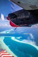Amazing view from seaplane in Maldives islands, atolls and tropical island resorts from above. Vertical travel landscape, panorama from plane window view. Exotic summer vacation, traveling photo