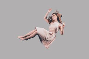 Woman in mid-air. Studio shot of attractive young woman hovering in air photo