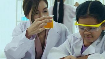 las colegialas asiáticas están estudiando ciencia y tecnología en un laboratorio. los maestros enseñan ciencias a los estudiantes para aprender habilidades de proceso. video