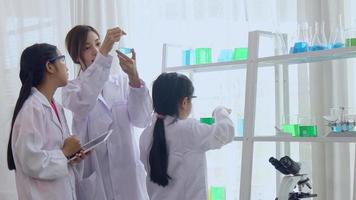 les écolières asiatiques étudient la science et la technologie dans un laboratoire. les enseignants enseignent les sciences aux élèves pour acquérir des compétences de processus. video