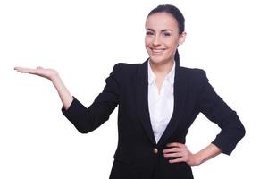 Copy space on her hand. Cheerful young woman in formalwear holding copy space and smiling while standing isolated on white photo