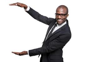 publicidad de su producto. un joven africano feliz con ropa formal sosteniendo un gran espacio para copiar y sonriendo mientras estaba aislado de fondo blanco foto