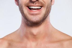 Feeling happy. Cropped image of handsome young shirtless man smiling while isolated on grey background photo