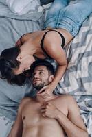 Simply in love. Top view of beautiful young semi-dressed couple lying face to face while spending time in the bedroom photo