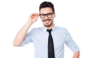 Cheerful businessman. Handsome young man in shirt and tie adjusting his eyeglasses and smiling while standing against white background photo