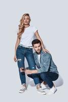 Denim style. Full length of beautiful young couple bonding while standing against grey background photo