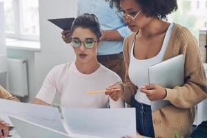 Two confident young women in smart casual wear discussing business while having meeting in office photo