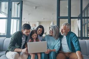 Happy family using laptop and smiling while spending time home together photo