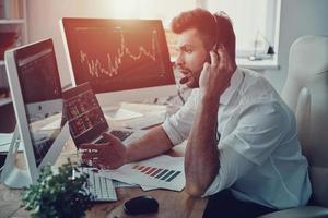 Available all day long. Young businessman in headset talking with client while sitting in the office photo