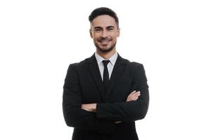 Confident and stylish.  Handsome young man in full suit keeping arms crossed and looking at camera while standing against white background photo